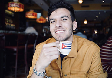 Photo of Jesús holding a coffee cup with a Puerto Rico flag